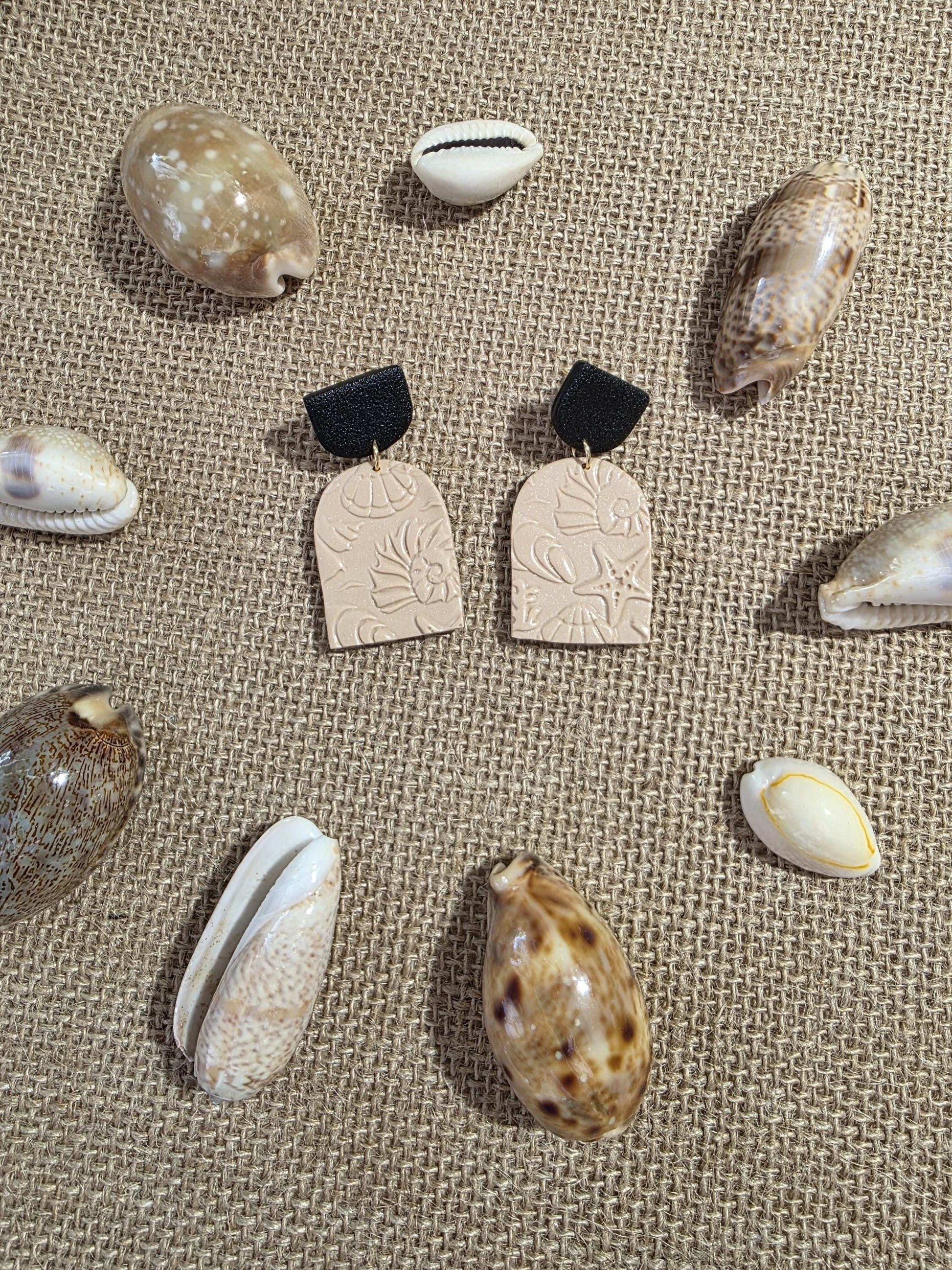Boucle d'oreille "Empreintes salées" (argile polymère couleur sable et noire aux motifs marins) Collection "Sous l'Océan" été 2025